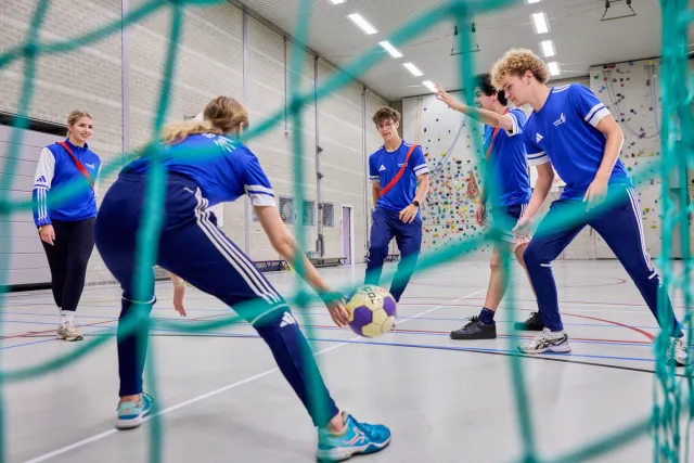 Sportstudenten voetballen binnen in gymzaal