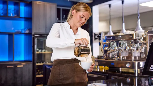 Student barista maakt cappuccino in leerrestaurant Lokaal