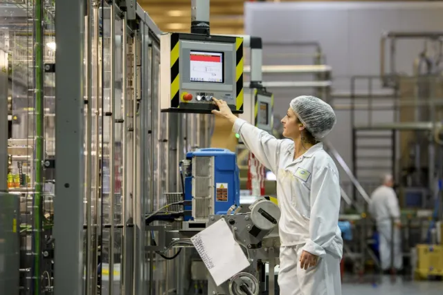 Een student in de praktijk die een controle uitvoert in de fabriek met een controlepaneel.