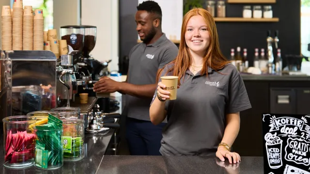 Student geeft koffie aan achter koffiebar