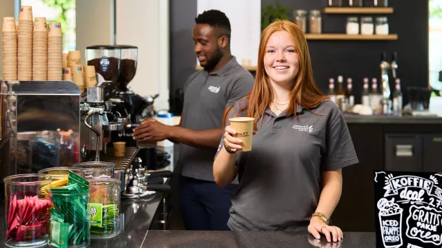 Student Horeca & Toerisme College geeft koffie aan gast achter coffeebar