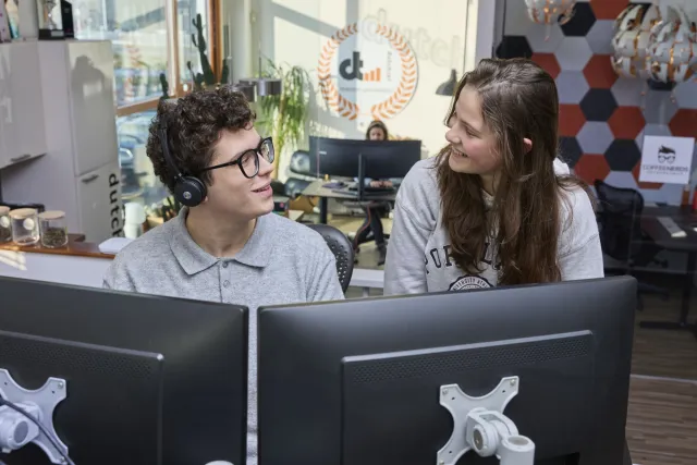 Student ICT praat met andere stagiair op kantoor