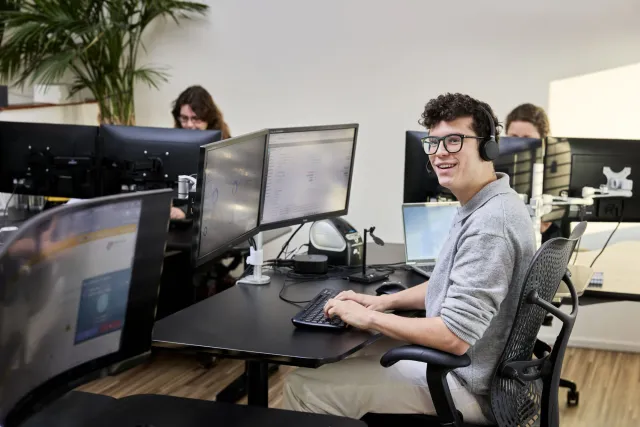 Student ICT werkt met plezier op computer op stageplek