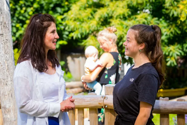 Gesprek tussen twee vrouwen bij een hek.