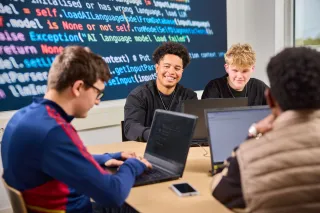 Studenten werken aan een ICT-project waarin ze moeten coderen achter de laptop