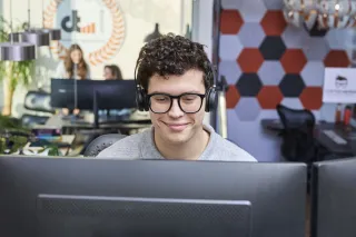 Student ICT werkt op computer met headset op