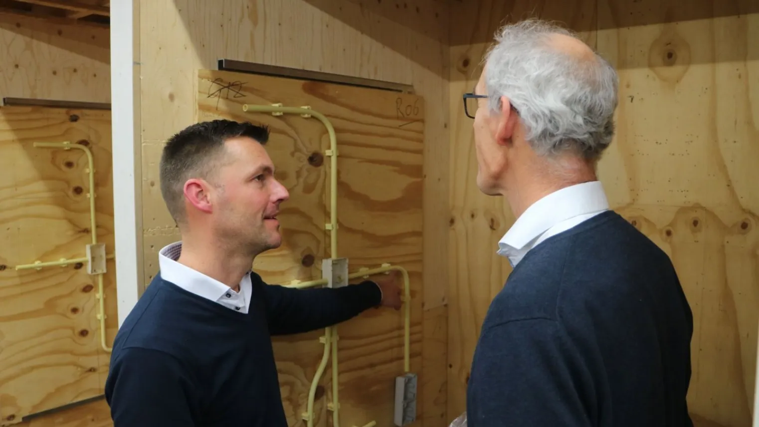 Een student en docent samen aan het overleggen bij elektrokast 