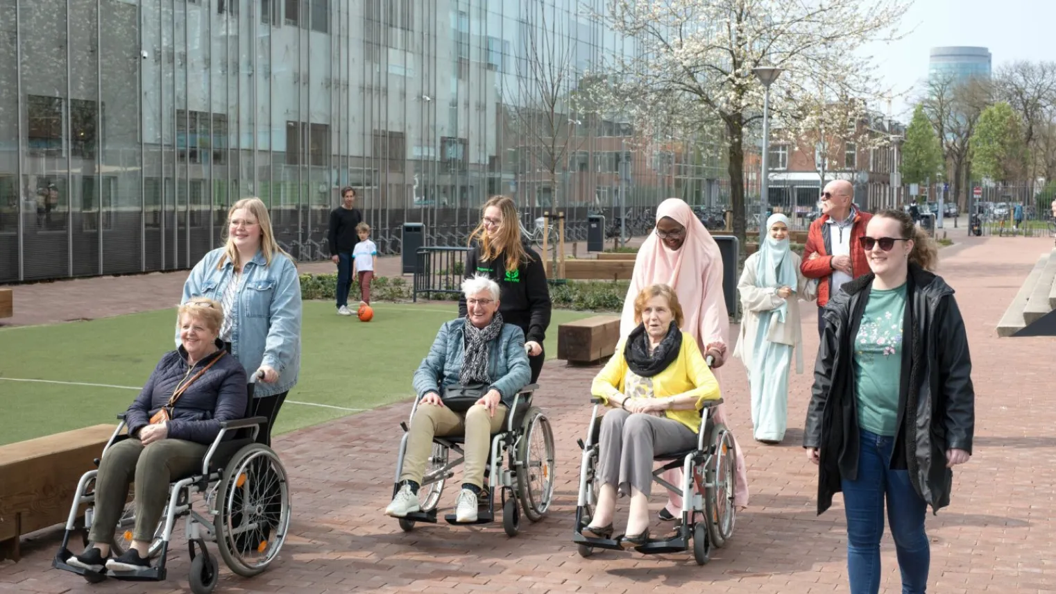 Studenten Persoonlijk Begeleider Maatschappelijke Zorg & Sociaal Werk lopen met cliënten buiten
