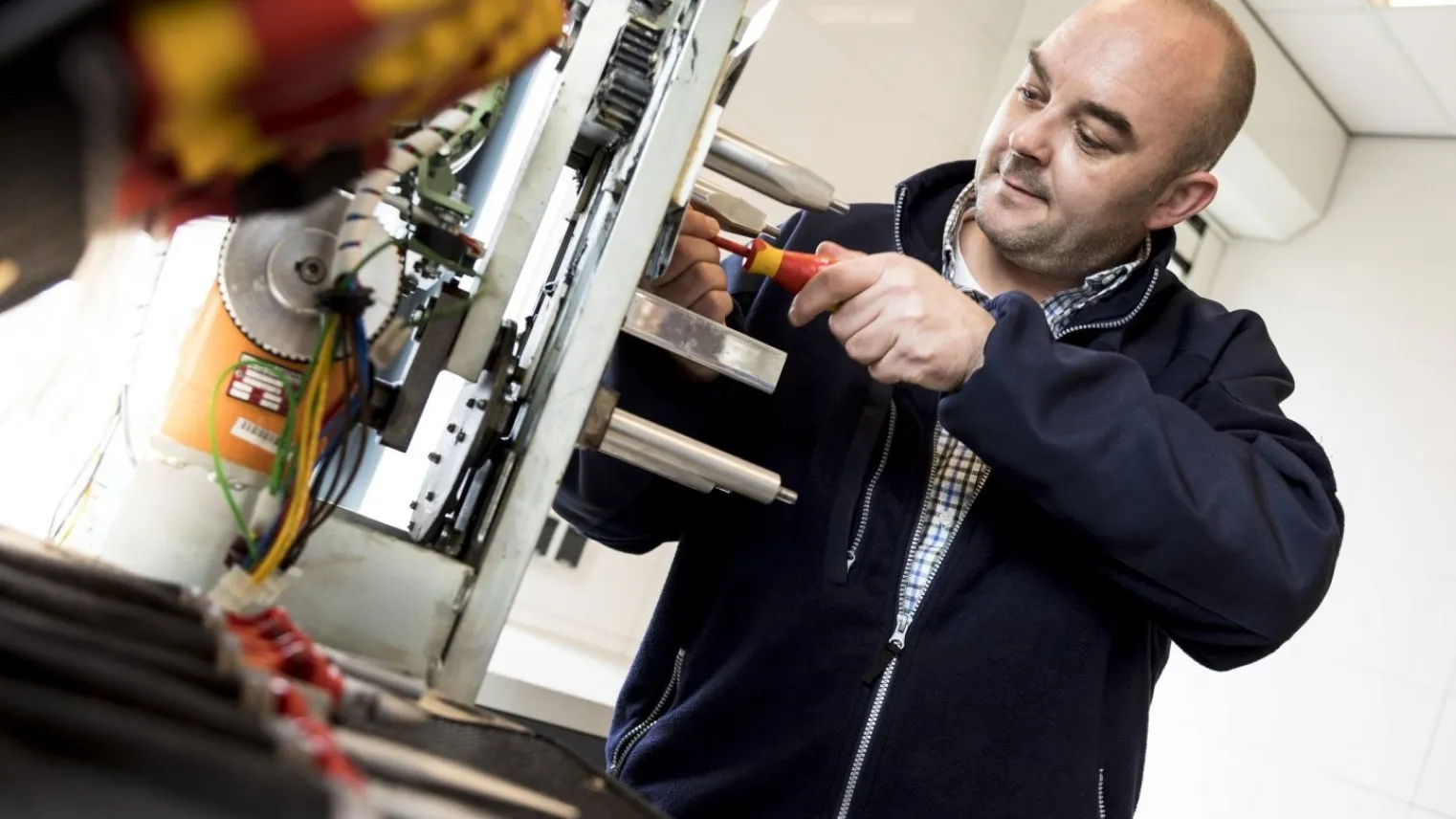 Student aan het werk bij een machine met een schroevendraaier 