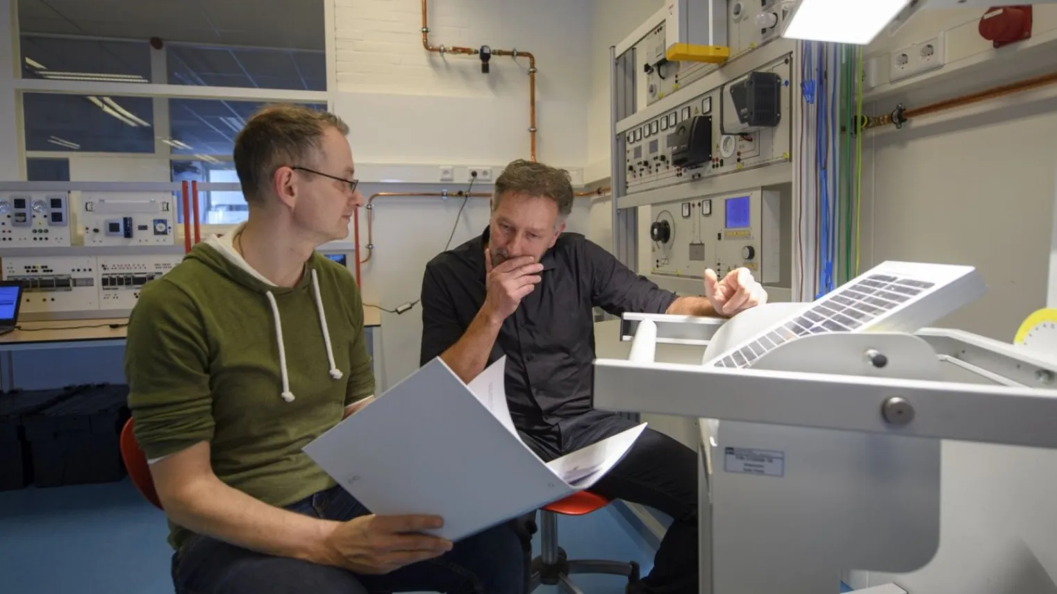 Een student Operator C warmte en energie in de praktijk met praktijkbegeleider voor een controlepaneel in de fabriek. 