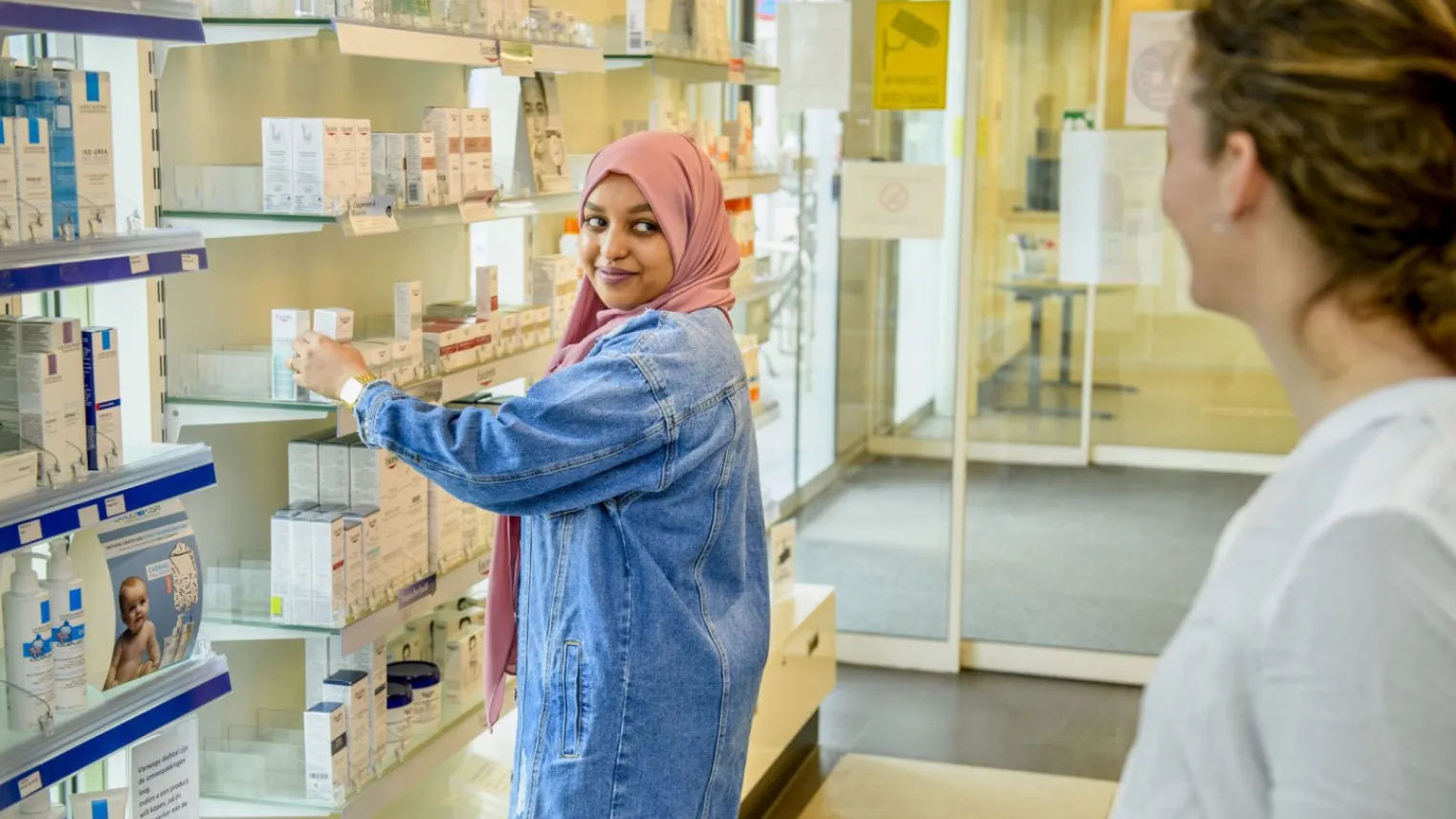 Apothekersassistent pakt medicijnen voor klant in apotheek.