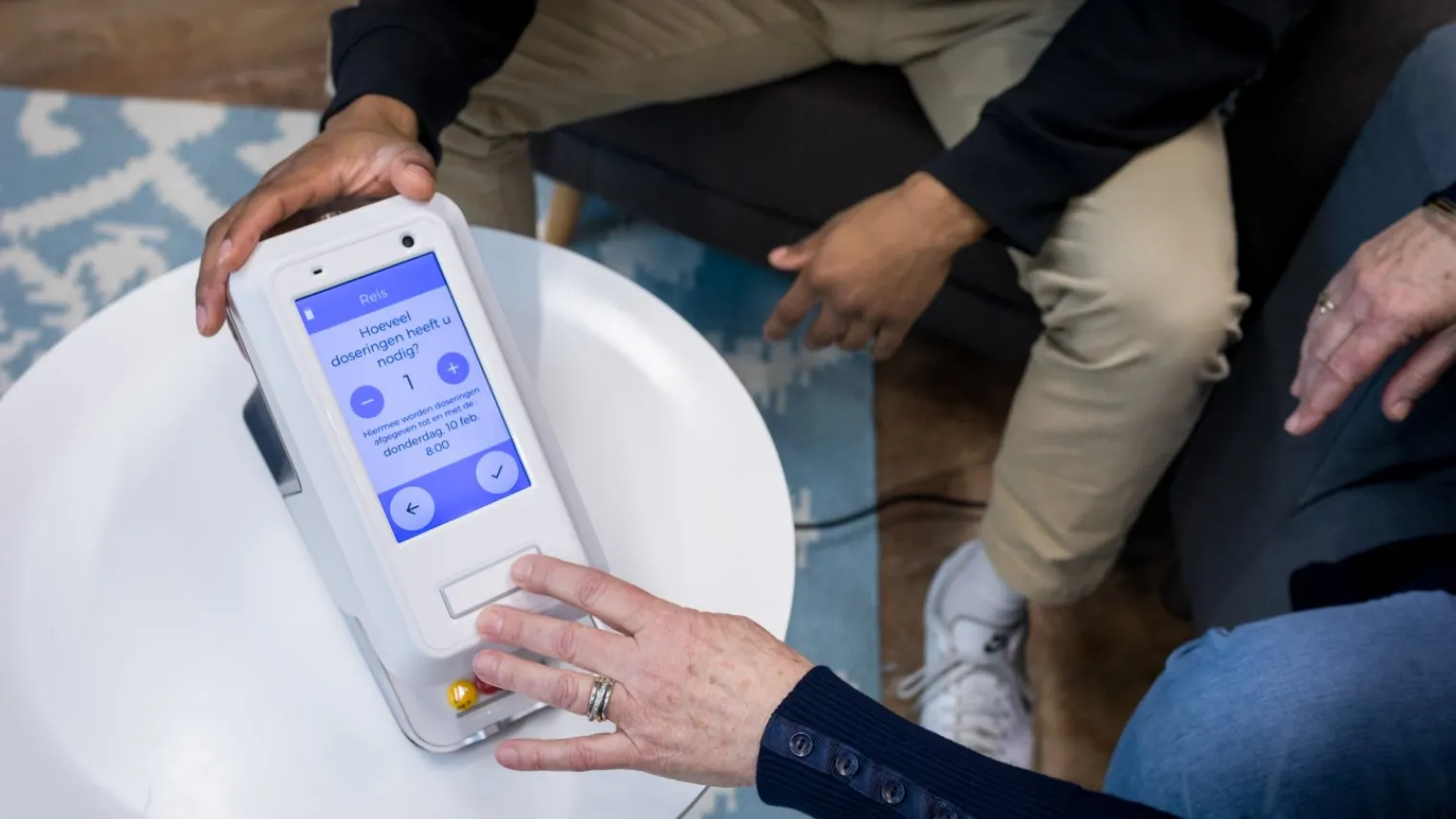 Een hand houdt doseerapparaat voor medicatie vast en andere hand drukt op knopje van apparaat.