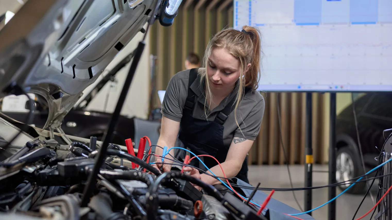 Student Autotechniek controleert elektriciteit onder de motorkap van een personenauto
