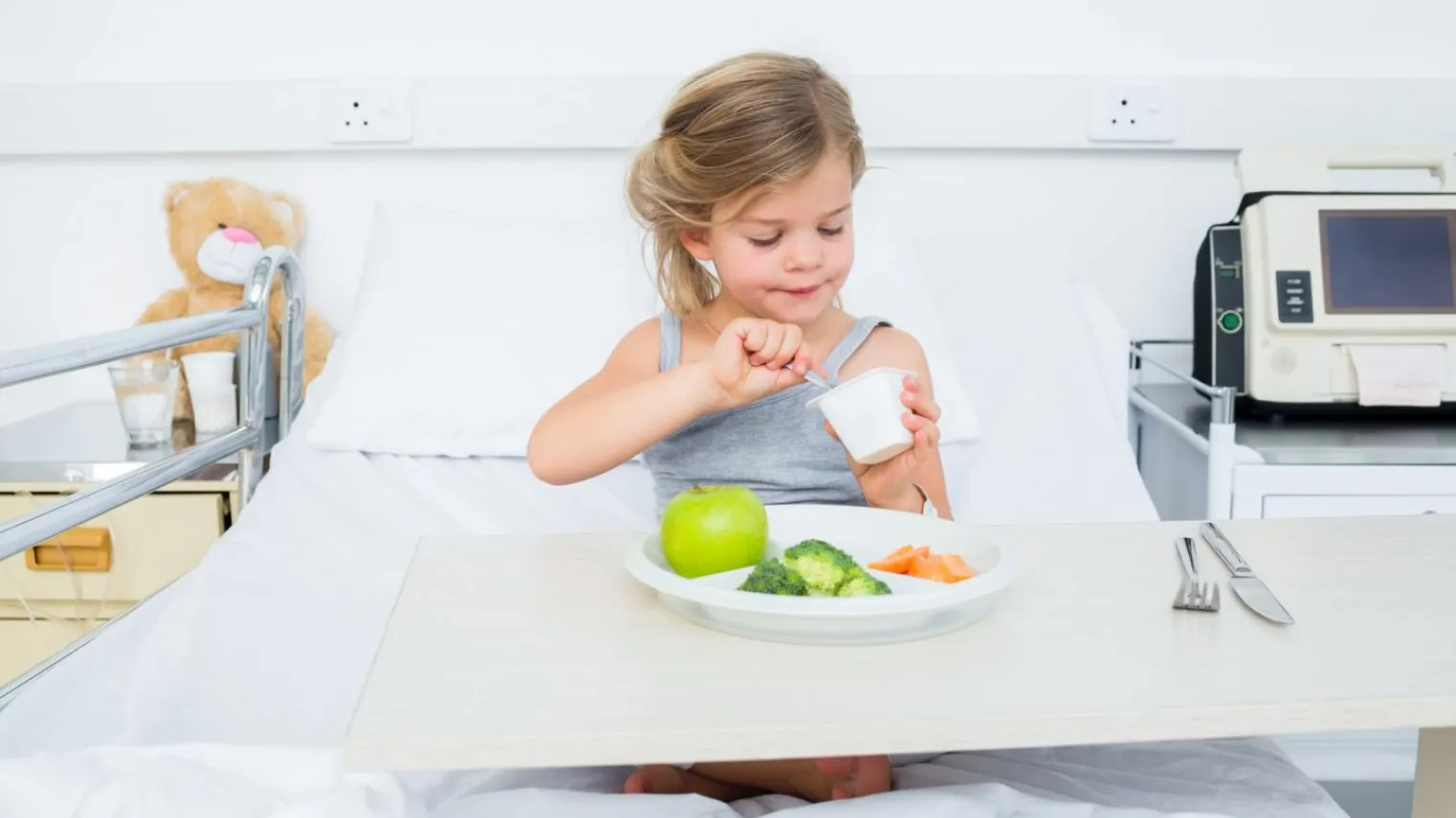 Kind in ziekenhuisbed is aan het eten.