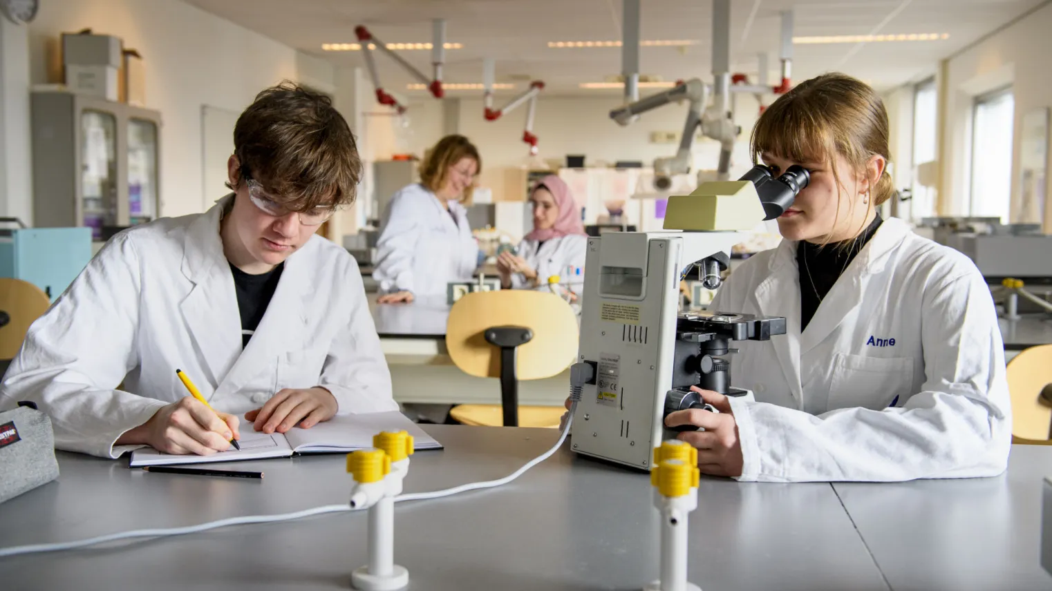 Twee studenten in laboratoriumjassen werken aan een project.