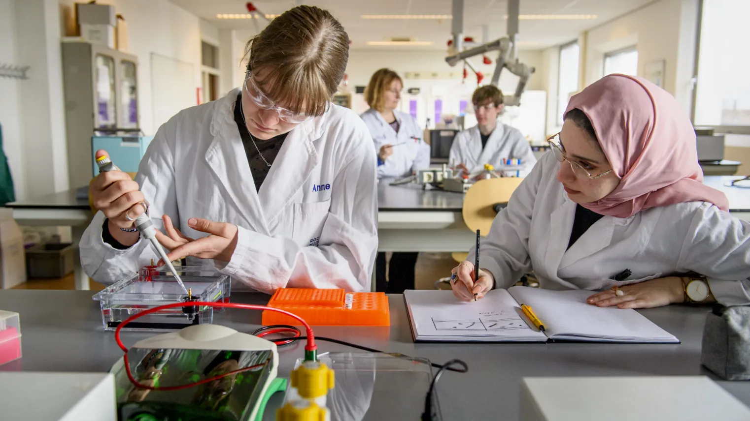 Twee vrouwen in laboratoriumjassen werken aan een project.