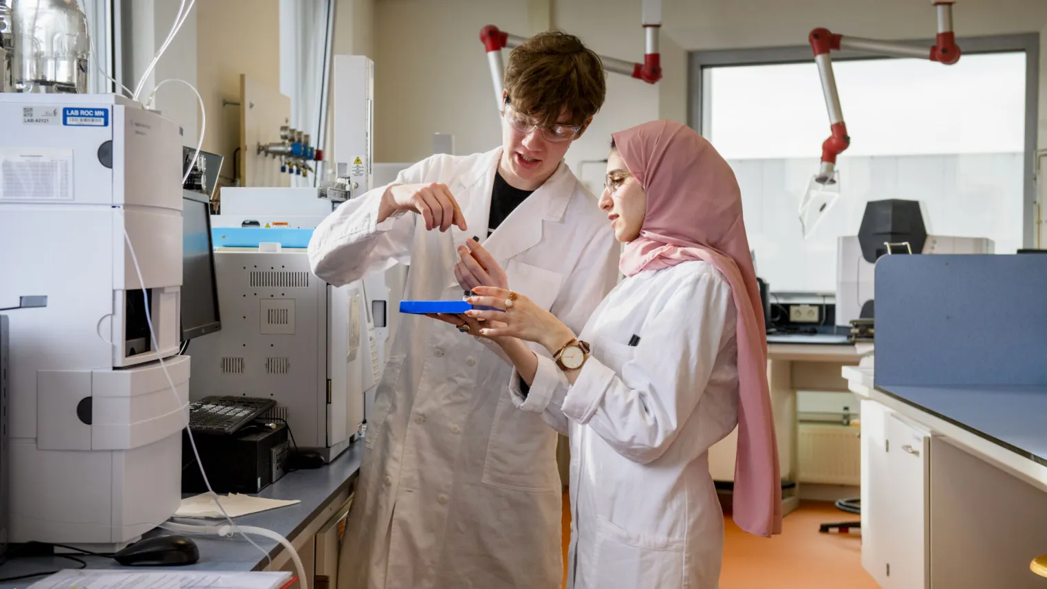 Twee personen in laboratoriumjassen doen een test in een proeflokaal.