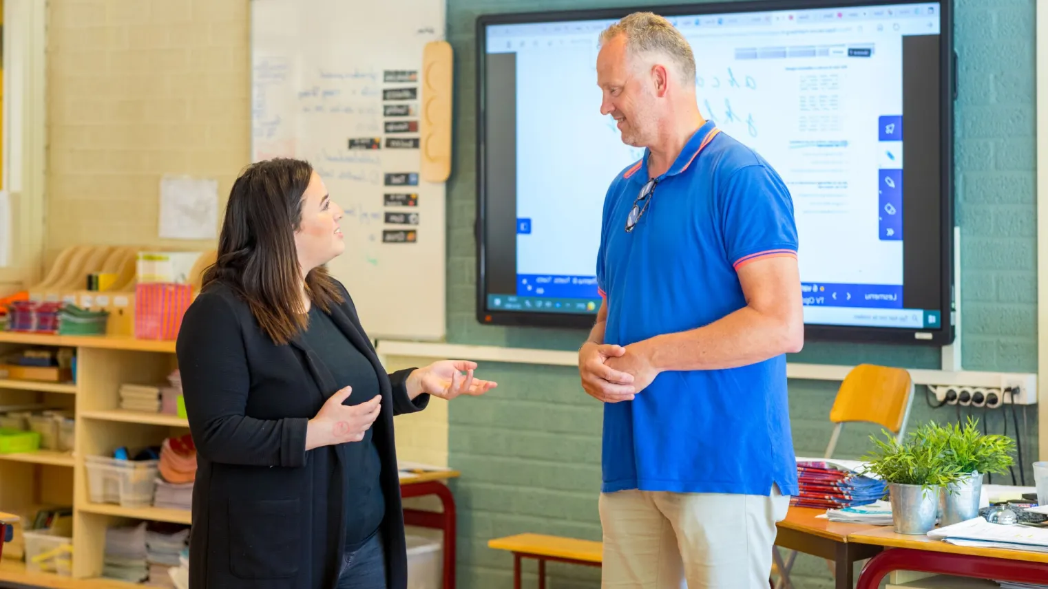 Instructeur praat met student in klaslokaal.