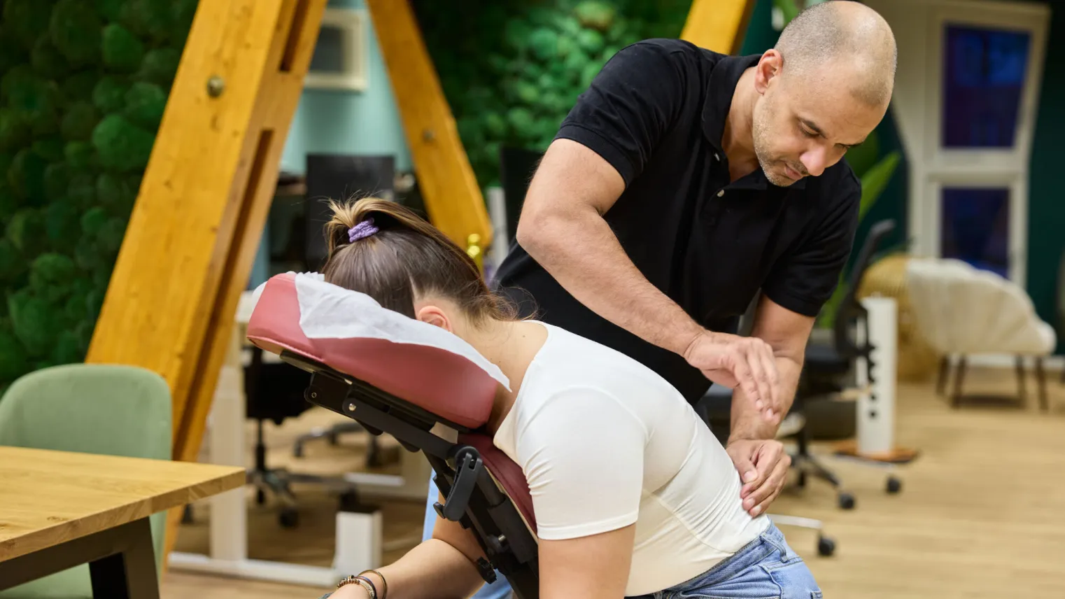 Een masseur geeft een vrouw een stoelmassage.