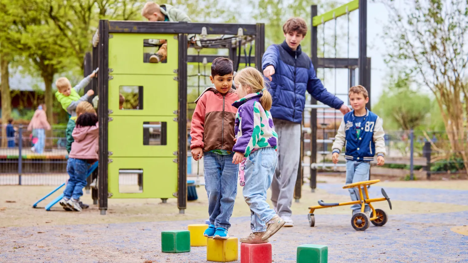 Pedagogisch medewerker begeleidt kinderen op het schoolplein
