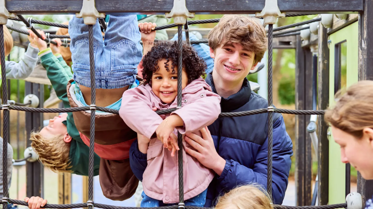 Pedagogisch medewerker speelt met leerlingen in het klimrek
