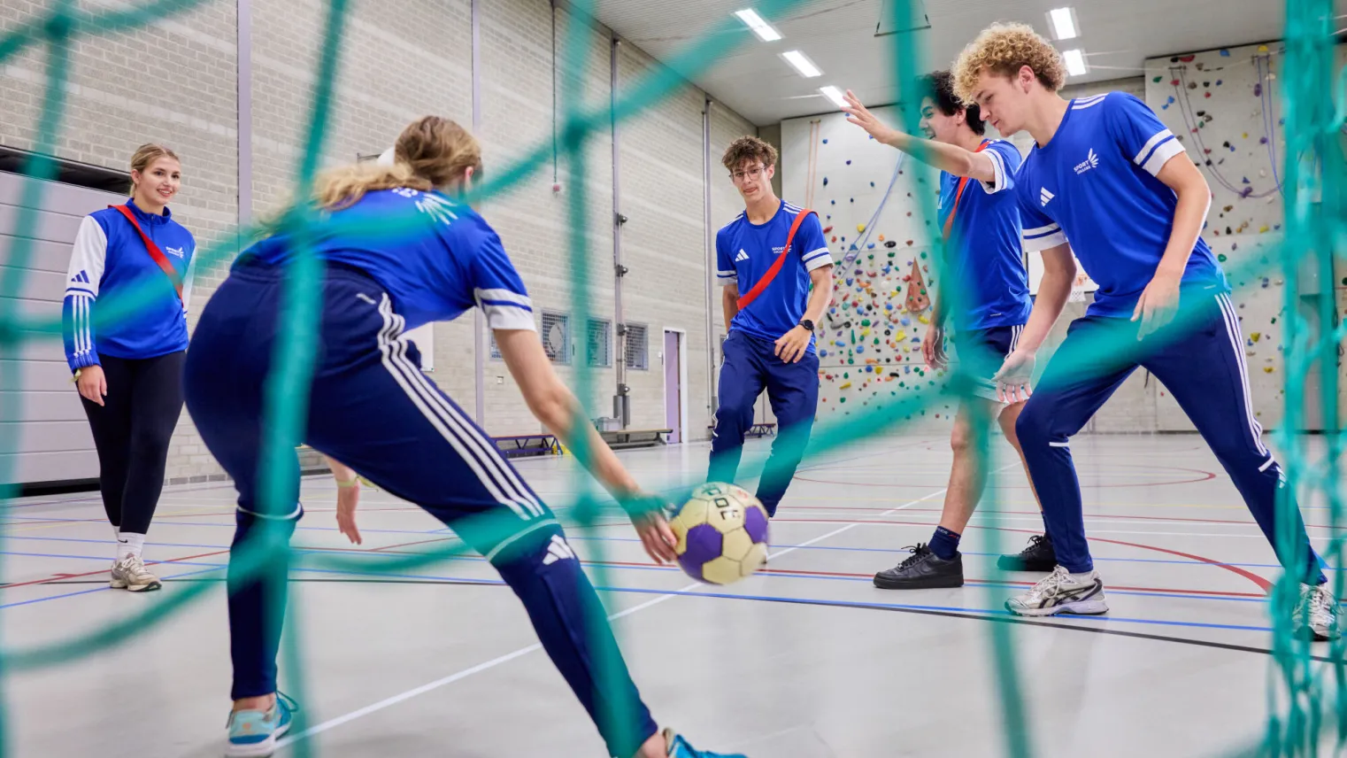 Sportstudenten voetballen binnen in gymzaal