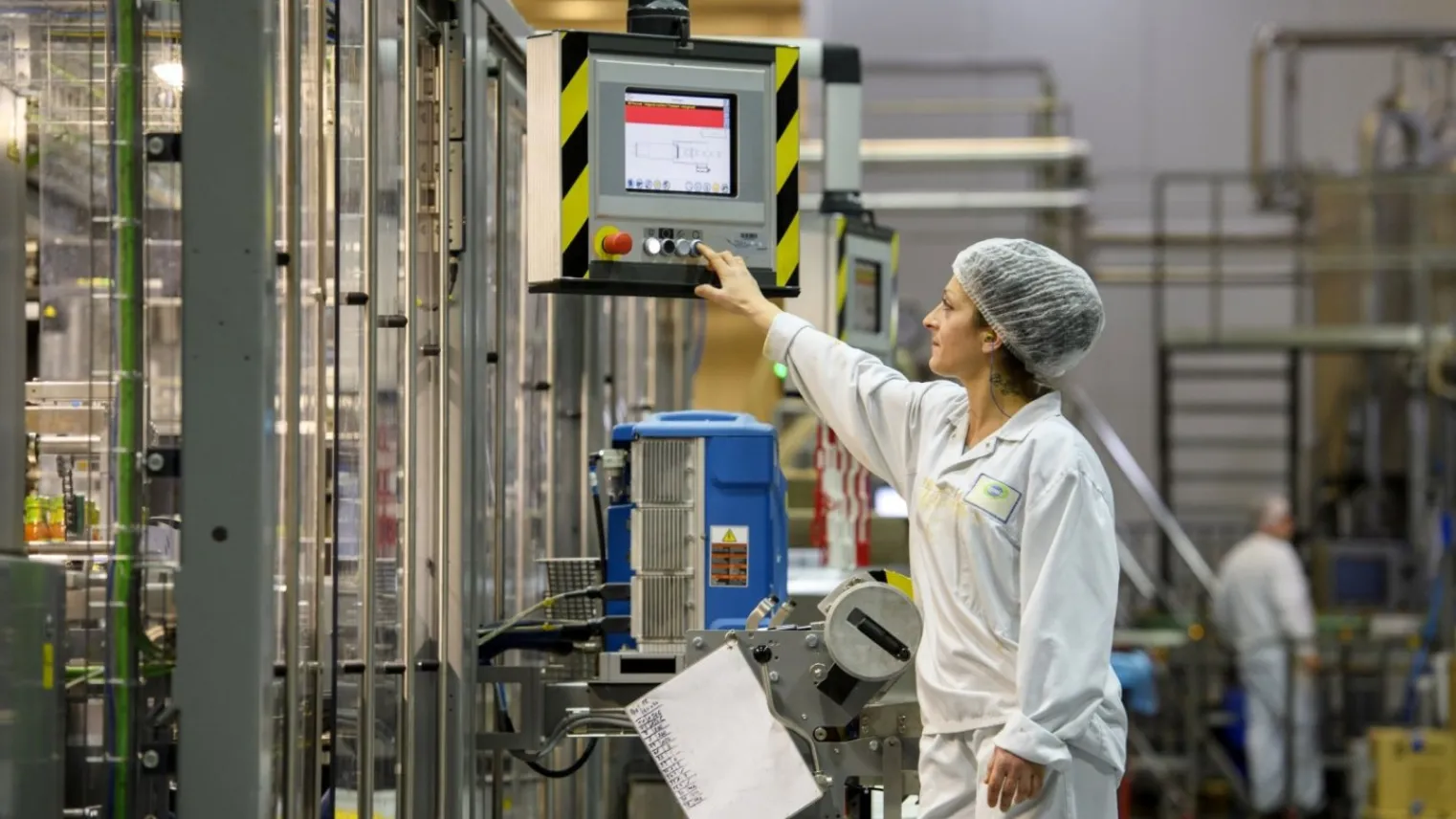 Een student in de praktijk die een controle uitvoert in de fabriek met een controlepaneel.
