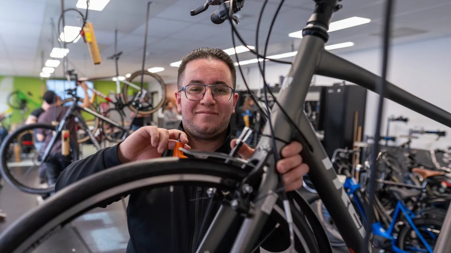 Student opleiding Fietstechnicus werkt aan fiets in werkplaats.