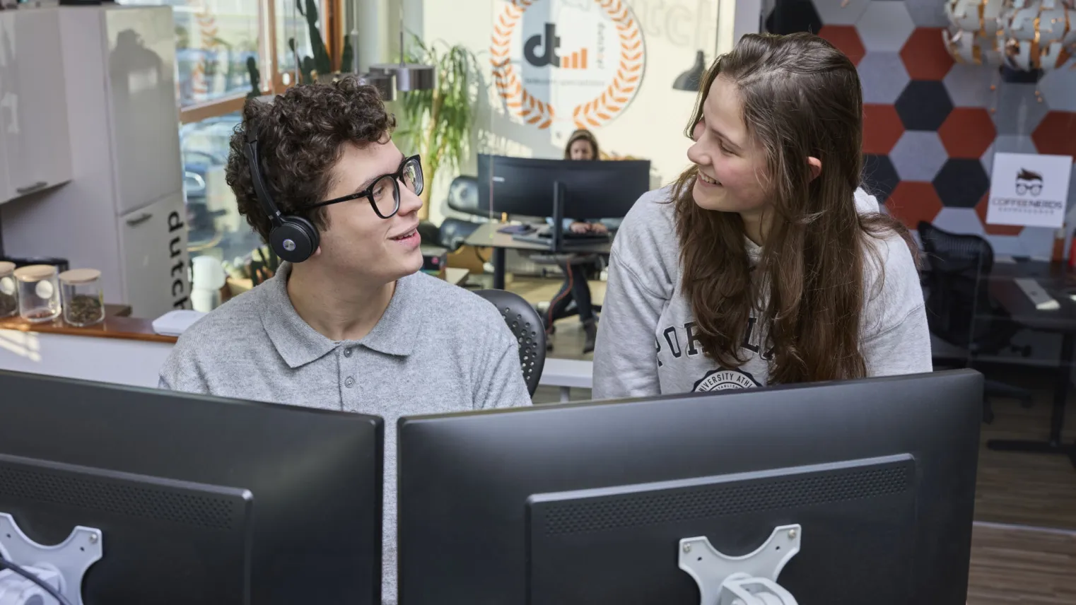 Student ICT praat met andere stagiair op kantoor