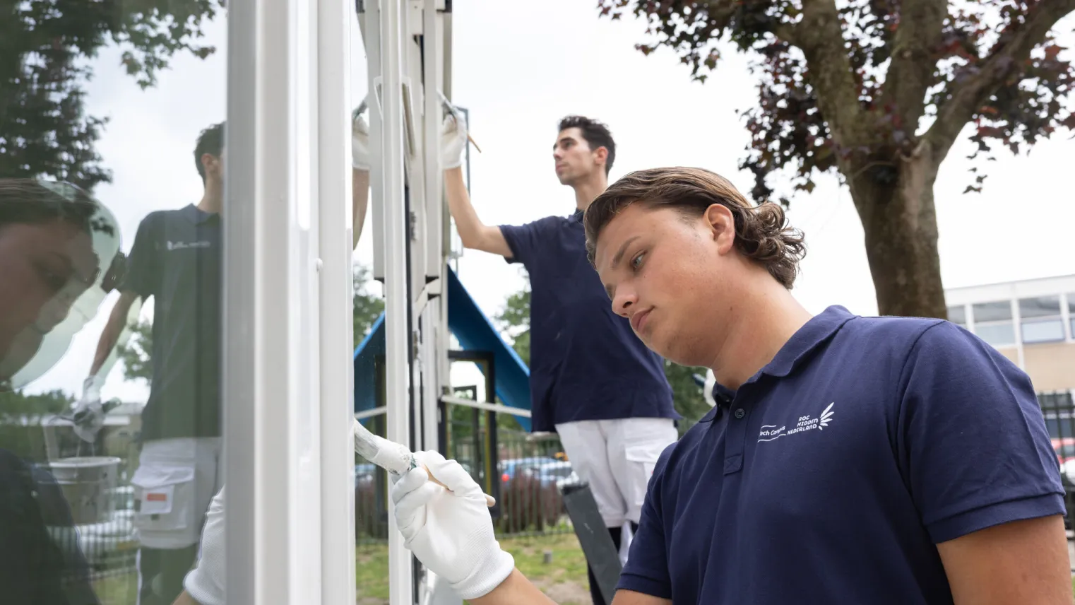 Studenten Schilder schilderen buiten kozijnen