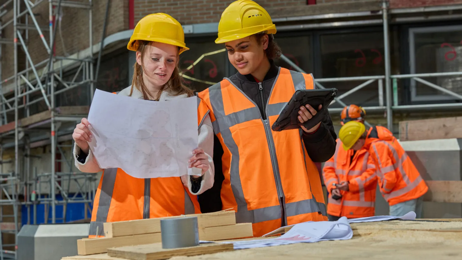 Studenten Bouwkunde overleggen met tekening en aantekeningen tablet