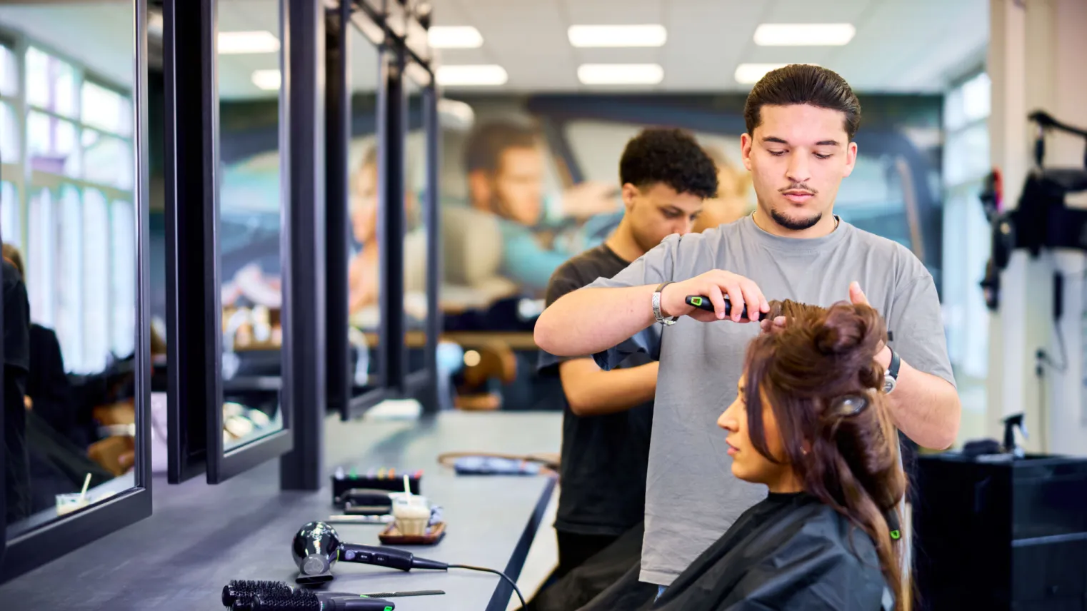 Student Haarstylist maakt het haar van een klant mooi