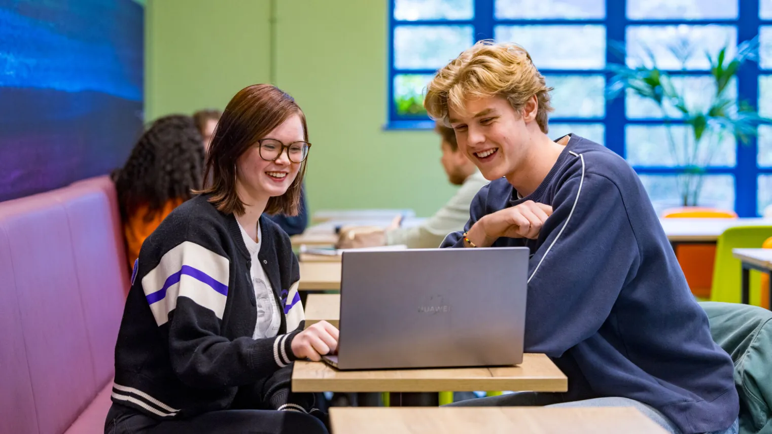 Studenten VAVO Lyceum werken samen op laptop in kantine