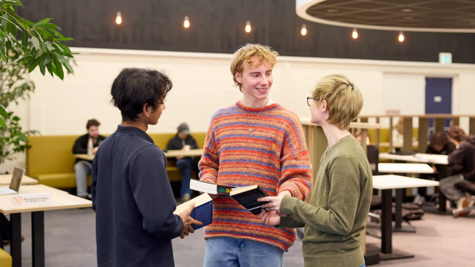 Studenten VAVO Lyceum praten met elkaar in de bibliotheek op school