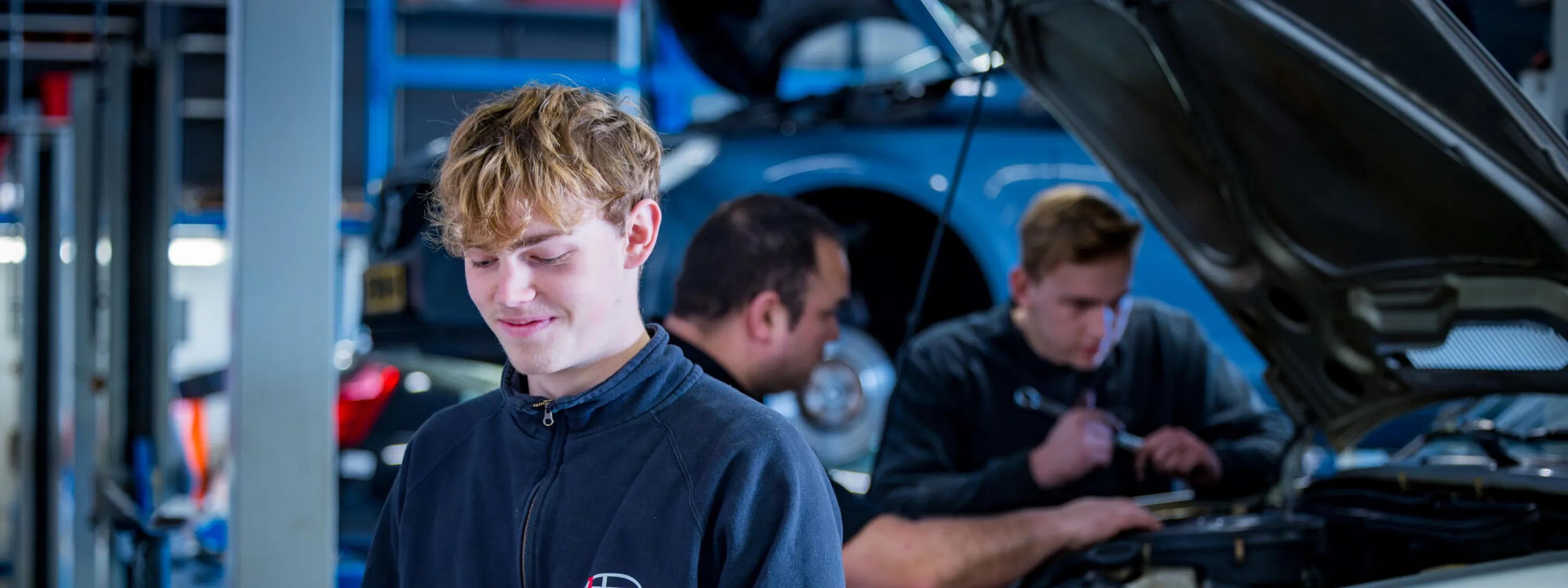 Student Autotechniek zoekt in de werkplaats iets op in een map