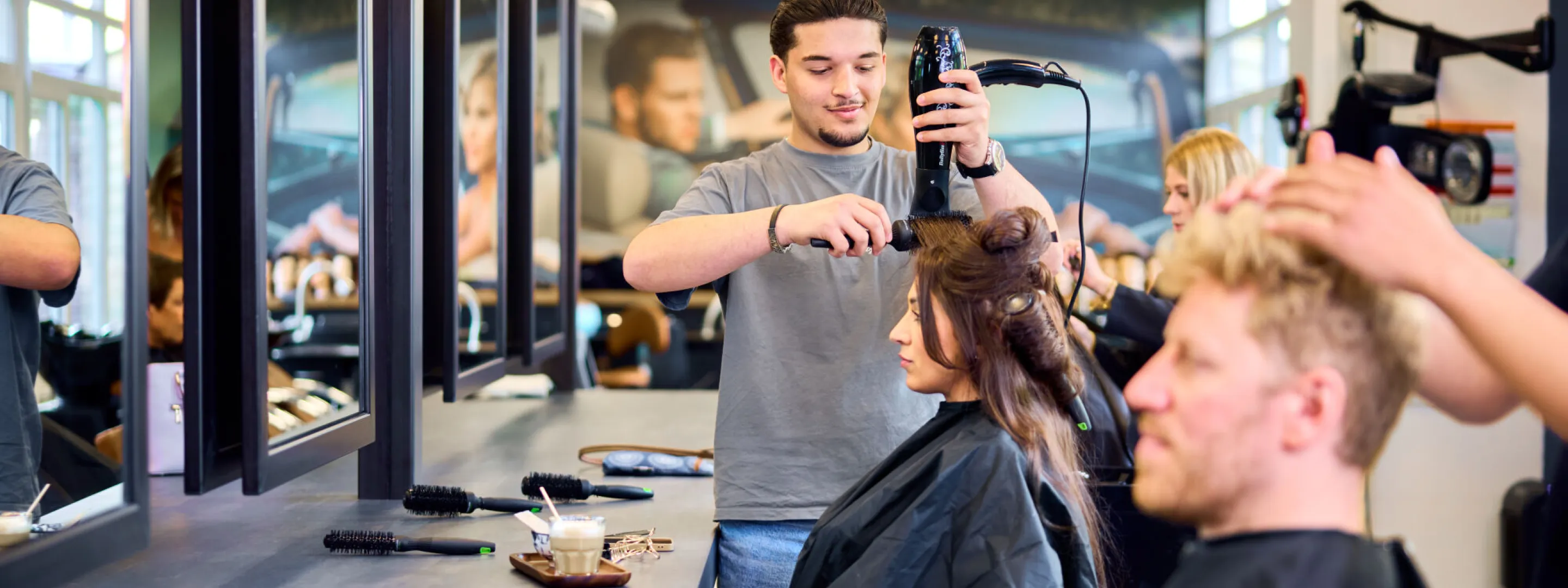 Studenten Kapper verzorgen het haar van klanten op het Beautyplein