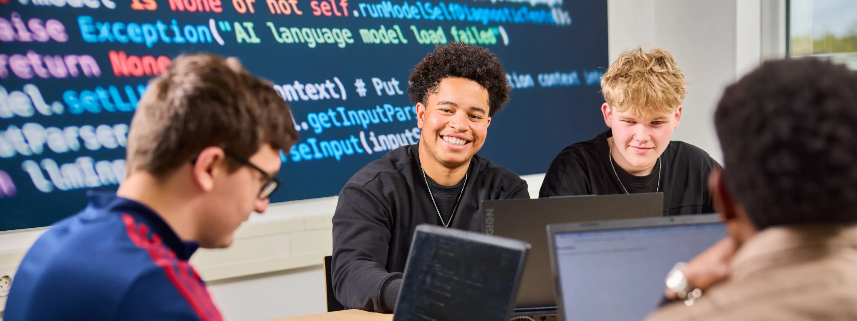 Studenten werken aan een ICT-project waarin ze moeten coderen achter de laptop