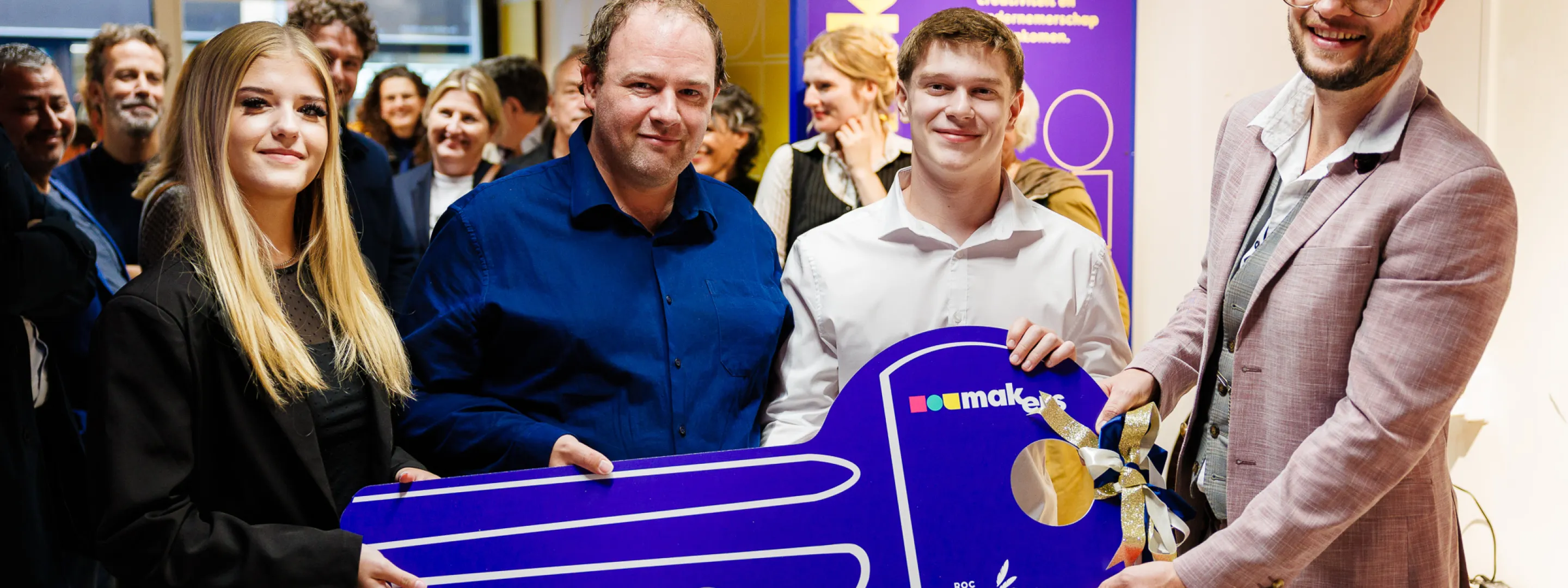 Studenten met wethouder openen winkel met grote blauwe sleutel