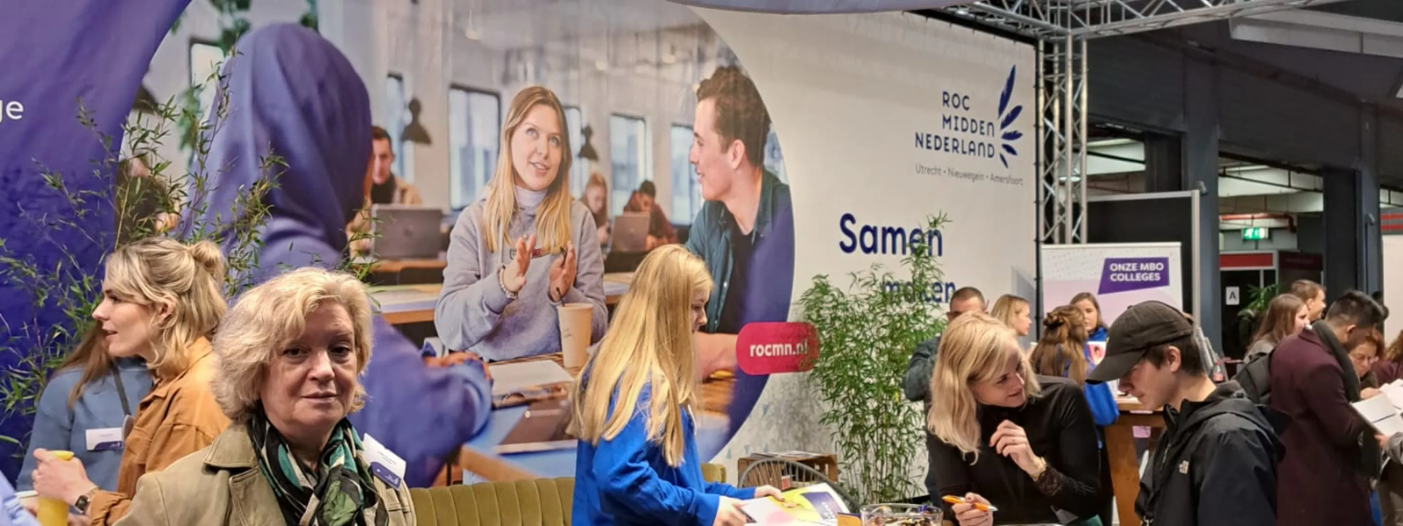 Student en voorlichter geven in de stand voorlichting aan studiekiezers
