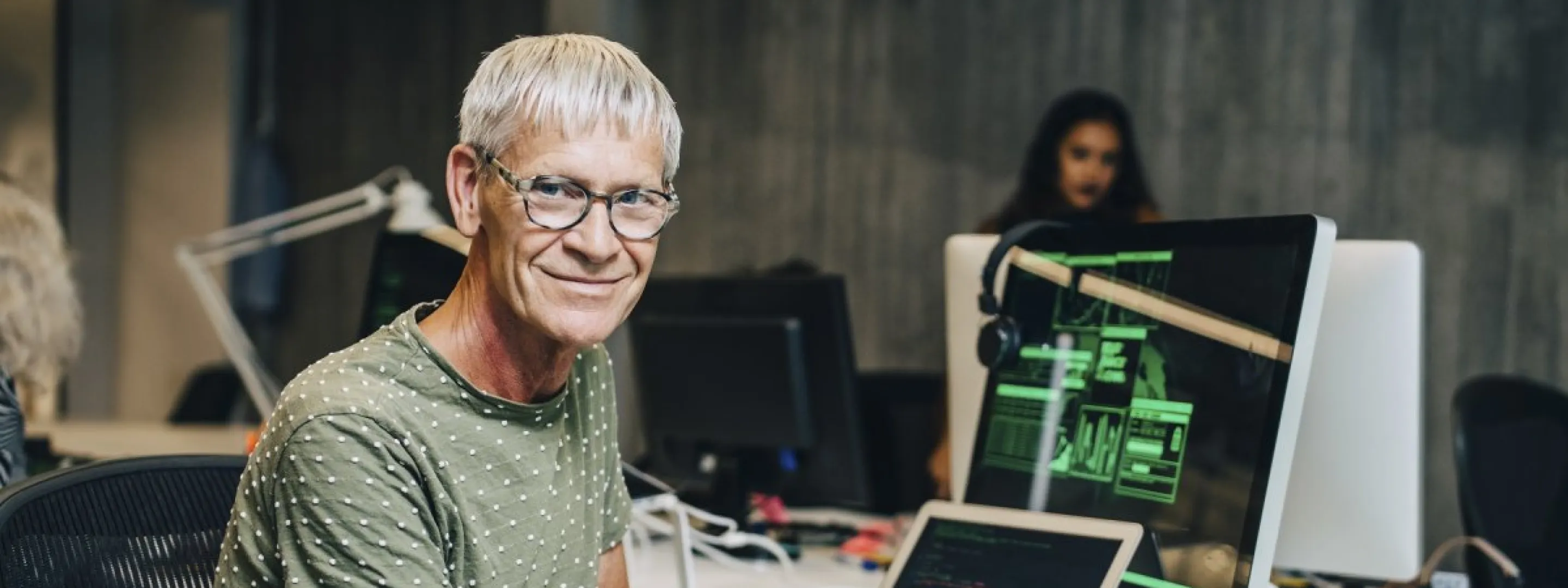Cursist ICT techniek kijkt in de cameralens. Op de achtergrond computers, kabels zichtbaar.