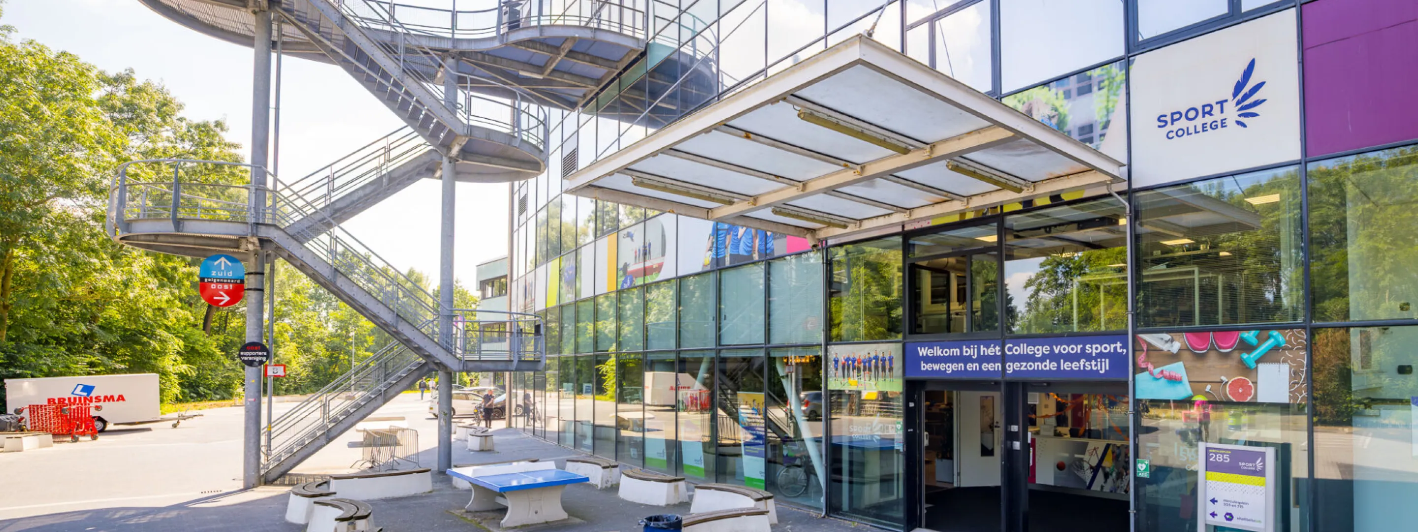 Ingang van het Sport College in stadion Galgenwaard in Utrecht met de buitentrap en zitbanken ervoor.