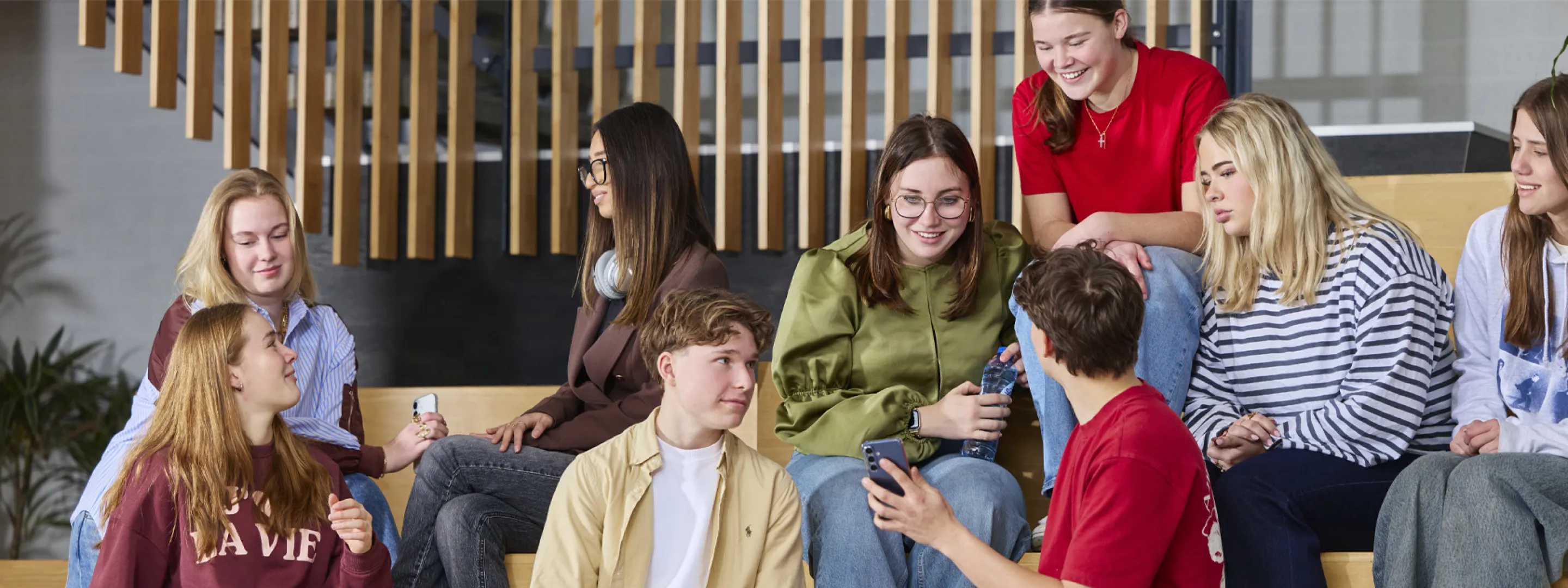 Groep studenten zit samen op een trap en praat ontspannen met elkaar