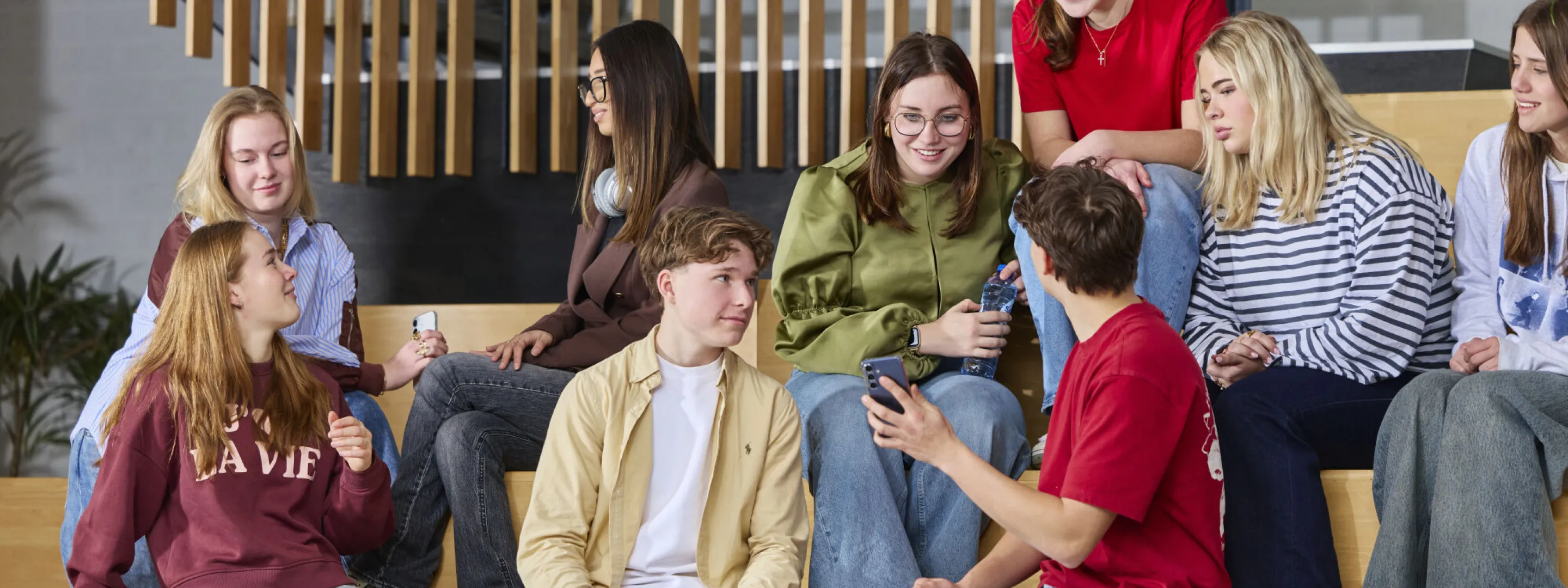 Groep studenten zit samen op een trap en praat ontspannen met elkaar