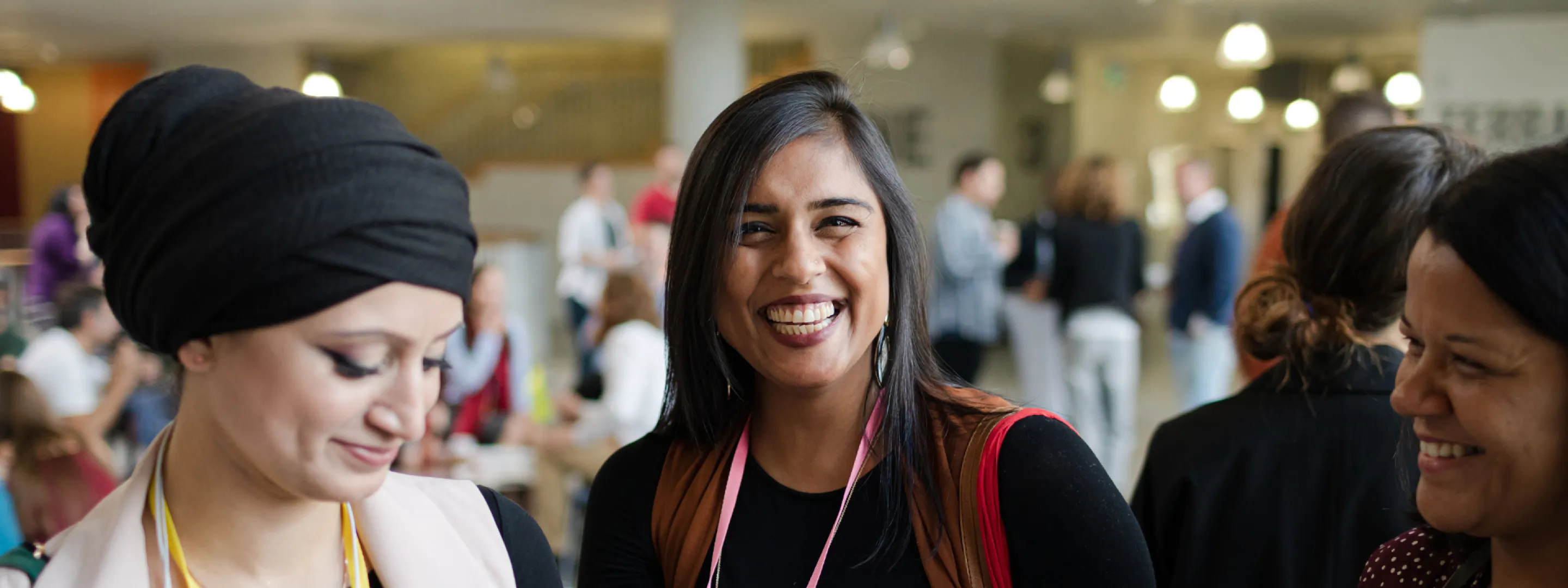Drie studenten praten en lachen in een schoolgebouw