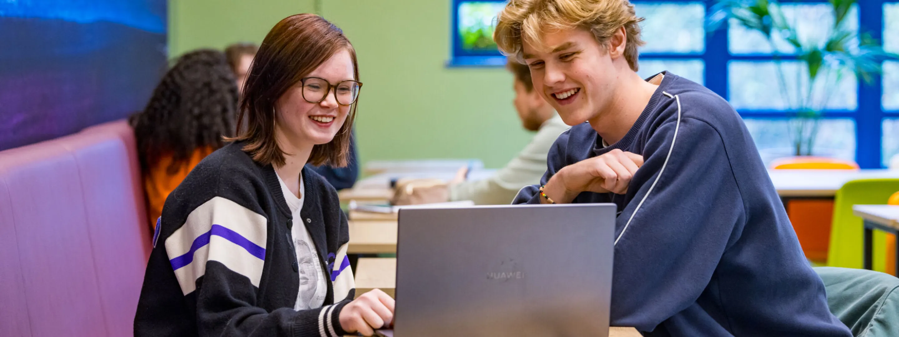 Studenten VAVO Lyceum werken samen op laptop in kantine