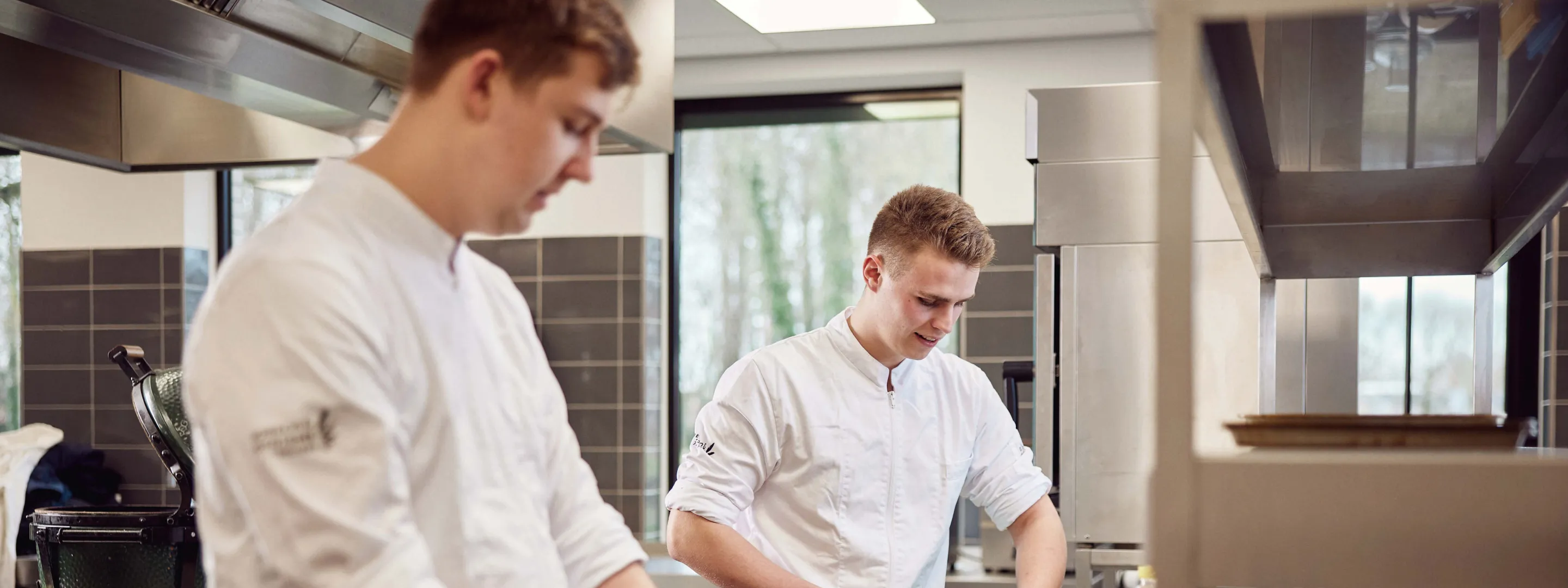 Twee studenten kok in witte uniformen werken samen aan de bereiding van maaltijden in een keuken